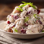 Close-up of creamy cranberry pecan chicken salad in a shallow white bowl featuring diced cooked chicken breast, dried cranberries, chopped pecans, celery, and green onions in a creamy mayonnaise and Greek yogurt dressing.