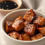 Close-up of air fryer salmon bites glazed with soy sauce on a white plate