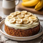 Close-up of a banana cake with cream cheese frosting on a clean background.