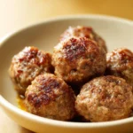 Close-up of Marry Me Meatballs with creamy sauce and herbs on a white plate.