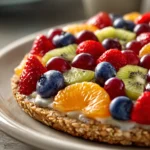 Close-up of oatmeal cookie fruit pizza with fresh fruits on a clean white background