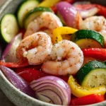 Close-up of shrimp and vegetables cooked in an air fryer, with bright colors and a clean background.