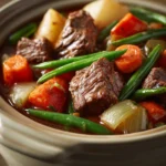 Close-up of slow cooker beef with vegetables in a bright, appetizing setting.
