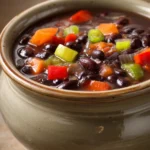 Close-up of slow cooker black bean soup with garnishes in a white bowl.