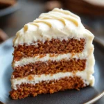 Close-up of carrot cake with cream cheese frosting, showcasing its texture and rich layers.