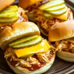 Close-up of a crock pot chicken sandwich with fresh ingredients and a clean background.