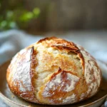 Close-up of freshly baked no knead bread with a golden crust on a wooden board.