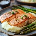 Close-up of a salmon dinner with vibrant vegetables on a white plate.
