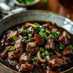 Close-up of slow cooker beef in black bean sauce with vibrant colors and textures.