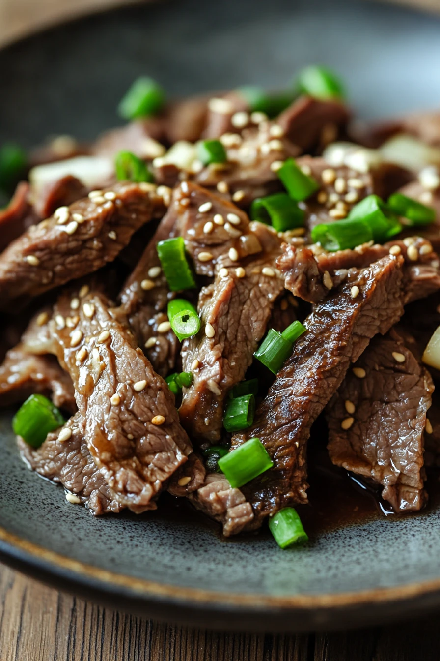 Close-up of slow cooker Korean beef with a rich, savory sauce and garnished with green onions.