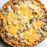 Chicken wild rice casserole - the image is of a freshly baked chicken pot pie on a white marble countertop. the pie has a golden brown crust on top and is filled with a mixture of chicken, mushrooms, carrots, celery, and other vegetables. the cheese is melted and bubbly, and there are small bits of herbs scattered throughout the dish. the dish appears to be freshly baked and ready to eat.