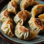 Air fryer vegetable dumplings - the image shows a plate of dumplings on a wooden table. the plate is round and has a dark brown rim. the dumpling in the center of the plate is golden brown and appears to be filled with a savory filling. the filling is made up of small pieces of meat and vegetables, which are arranged in a circular pattern on the plate. the meat is covered in a layer of orange-colored sauce, which is drizzled over the top of the filling. there are also some small pieces scattered around the plate, adding a pop of color to the dish. the overall appearance of the dish is appetizing and inviting.