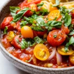 Cherry tomato pasta sauce freezer - the image is a close-up of a bowl of pasta dish. the dish appears to be a tomato-based pasta dish with chunks of cherry tomatoes, onions, and basil leaves mixed in. the tomatoes are bright red and appear to be ripe and juicy. the onions are sliced and the basil leaves are scattered throughout the dish, adding a pop of green color. the bowl is made of ceramic and has a speckled texture. the background is white, making the colors of the dish stand out.