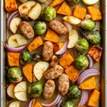 Sheet pan chicken sausage fall - the image shows a baking tray lined with parchment paper. on the tray, there are various types of vegetables, including brussels sprouts, apples, and red onions. the vegetables are arranged in a circular pattern, with some overlapping each other. the apples are cut into small cubes and are placed on top of the vegetables. the red onions are scattered throughout the tray. the tray is sitting on a white wooden surface.